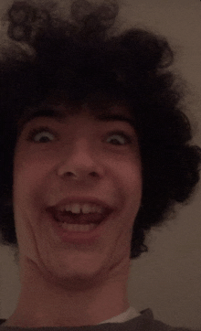 a young man with curly hair makes a funny face with his mouth open