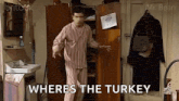 a man in pajamas is standing in a room next to a closet .