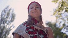 a woman wearing a red headband and a floral dress smiles for the camera