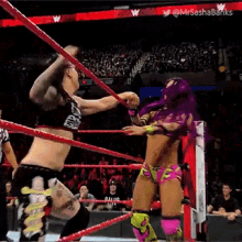 a female wrestler with purple hair is fighting a man in a wrestling ring