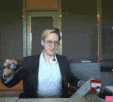 a man in a suit and glasses is sitting at a desk with a red box that says ' subscribe ' on it