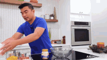 a man in a blue shirt is preparing food in a kitchen with a bottle of kraft macaroni and cheese on the counter