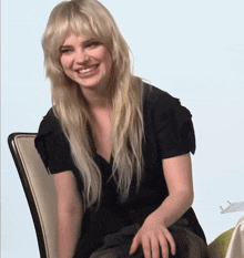 a woman with blonde hair is sitting in a chair