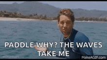 a man in a wetsuit is standing in the ocean and asking why the waves take him .