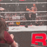 a man and a woman are wrestling in a wrestling ring with a crowd watching