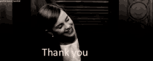 a woman is smiling in a black and white photo with the words thank you behind her