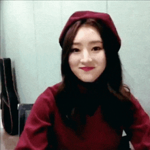 a young woman wearing a red beret and a red sweater is sitting at a table .