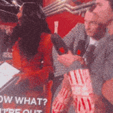 a man is holding a microphone in front of a sign that says " now what "