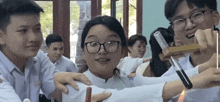 a girl wearing glasses is surrounded by a group of students