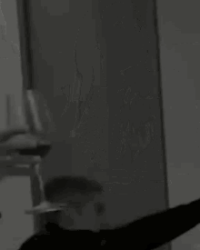 a black and white photo of a man holding a glass of wine in front of a mirror .