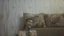 a man sitting on a couch holding a bottle of beer