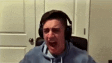 a man wearing headphones is screaming while sitting in a chair in front of a door .