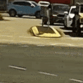 a yellow car is driving down a street next to a blue car .