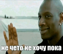 a man is smiling and waving his hand in front of a sign that says " he cheto he xomy poka "