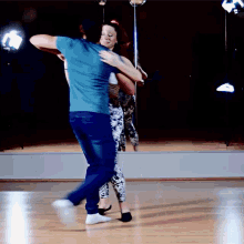 a man in a blue shirt is dancing with a woman