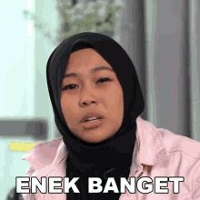 a woman wearing a hijab and a pink jacket has the word enek banget written on her face