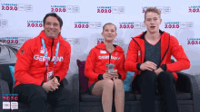 three people sit on a couch in front of a wall that says 2020