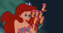 ariel from the little mermaid is holding a bunch of seahorses in her hand .