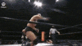 a wrestler is doing a handstand in a wrestling ring while a referee looks on ..