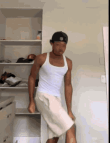 a man wearing a white tank top and shorts is standing in front of a closet