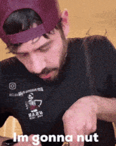 a man wearing a hat and a black shirt with a skeleton on it says " im gonna nut "