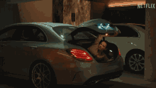 a woman is sitting in the back of a car with the trunk open and a netflix logo behind her