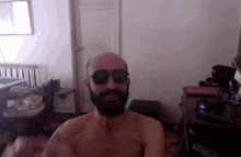 a shirtless man with a beard wearing sunglasses in a room