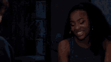 a man and woman are looking at each other in a dark room