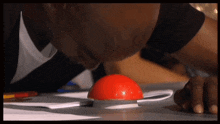 a bald man is pressing a red button on a table