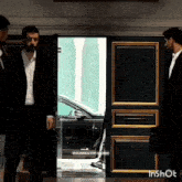 a man in a suit stands in front of a door that says ' inshot ' on it