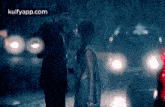 a man and a woman are kissing in the rain while standing next to each other .