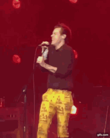 a man is standing on a stage singing into a microphone .