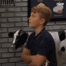 a young boy stands in front of a brick wall with a sign that says nick on it