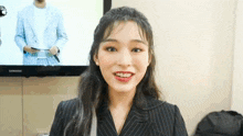 a woman in a suit is smiling in front of a samsung tv .