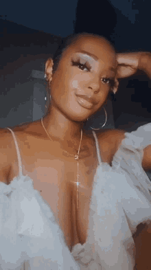 a woman wearing a white top and hoop earrings