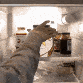 a person is reaching into a fridge with jars of jam and sauce