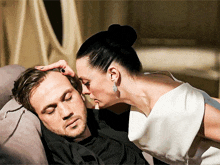 a woman kisses a man 's forehead while he sleeps