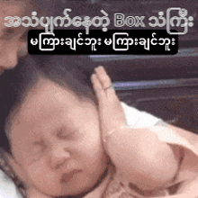 a woman is holding a baby in her arms and touching his ear with her hand .