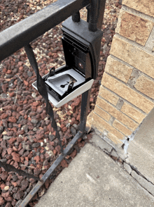 a key box is sitting on a railing next to a brick building