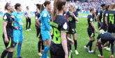 a group of female soccer players standing on a field with one wearing number 28