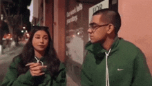 a man and a woman are standing next to each other in front of a building that says for rent