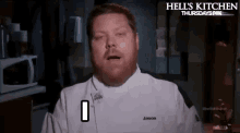 a man in a chef 's uniform is making a funny face while standing in a kitchen .