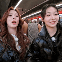 two girls are sitting next to each other on a bus and smiling for the camera