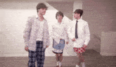 three men are standing next to each other in an empty room .