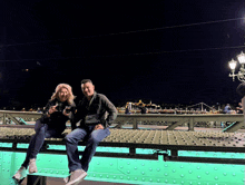 a man and a woman are sitting on a bridge holding glasses of wine