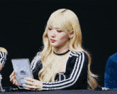 a woman with blonde hair wearing a black and white striped shirt with the letter ld on it