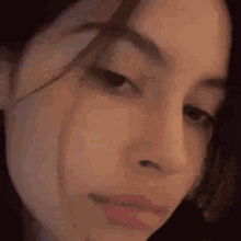 a close up of a woman 's face with a pink glowing nose ring .