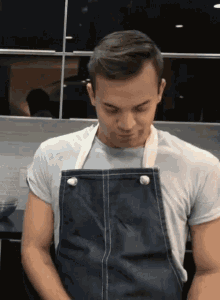 a man wearing a blue apron and a white t-shirt