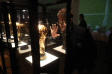 a man stands in front of a display case with a trophy in it