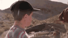a boy wearing a baseball cap and a shirt that says ' sharks ' on it